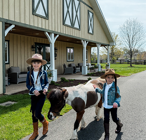 two girls walk with mini horse