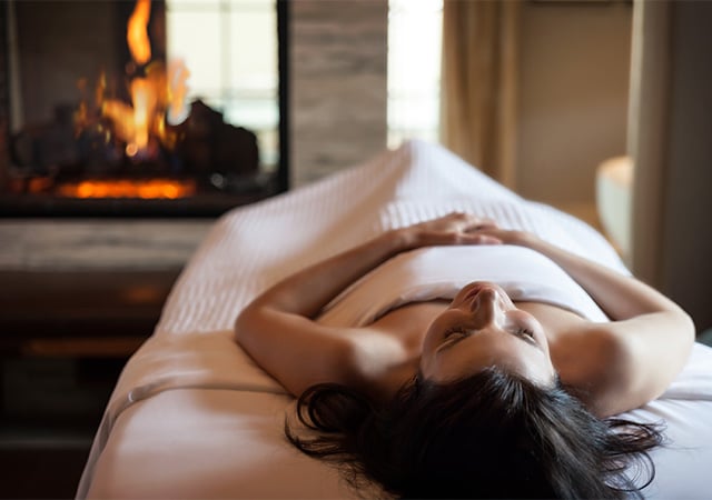 woman laying on spa treatment table with fireplace in the background