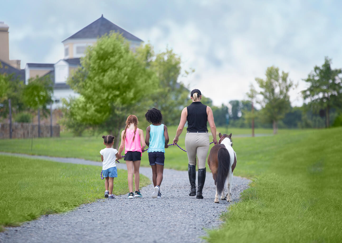 Family walking on a gravel path with a pony