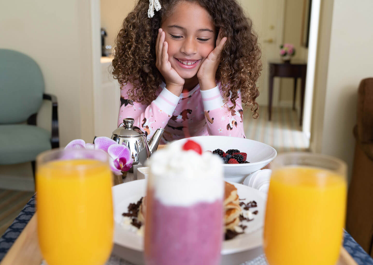 Small girl with room service juice, pancakes, and berries